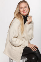 Woman wearing a beige cardigan sitting on a white background