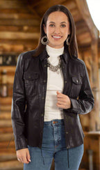 A woman wearing a black leather jacket with a western cut, snap front closure, chest pockets, and sleeve cuffs. She is also wearing a white top and blue jeans.