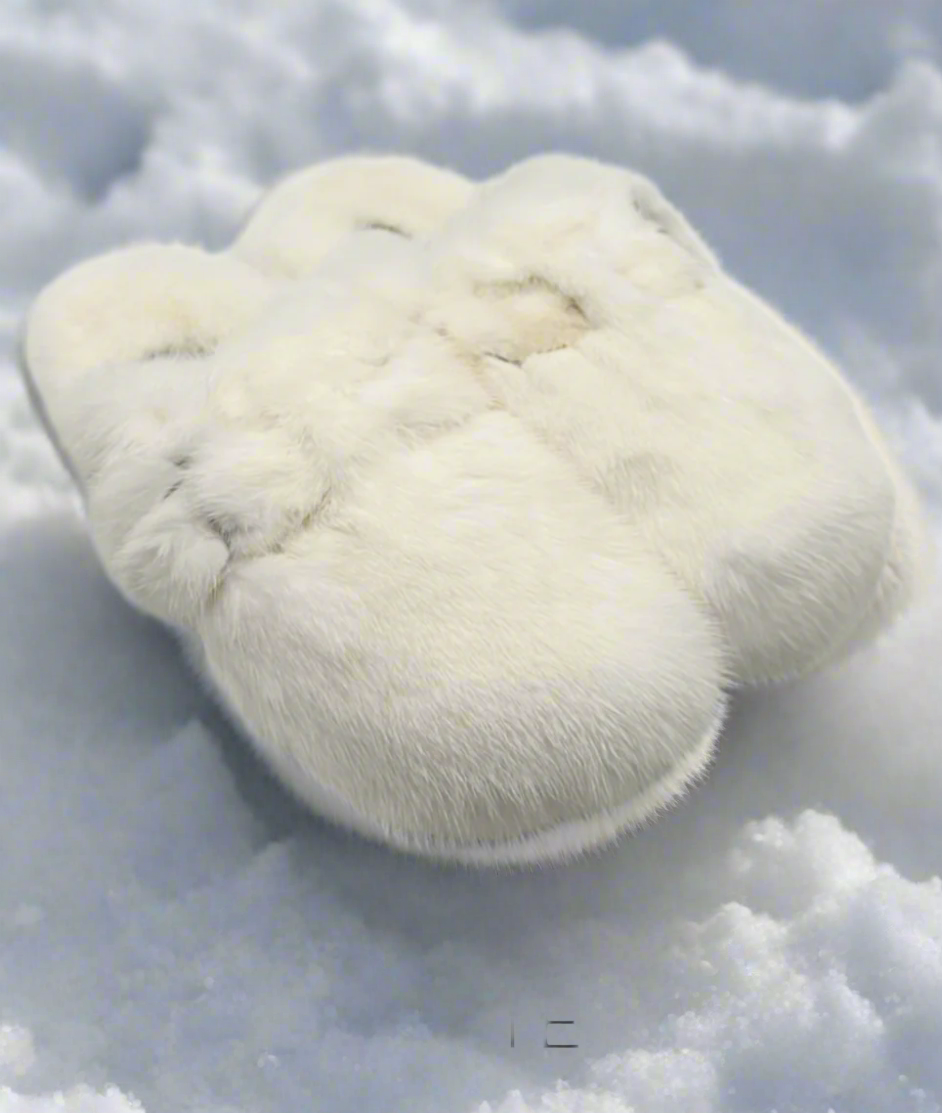 A pair of white mink fur clog style slides with adjustable side buckles.