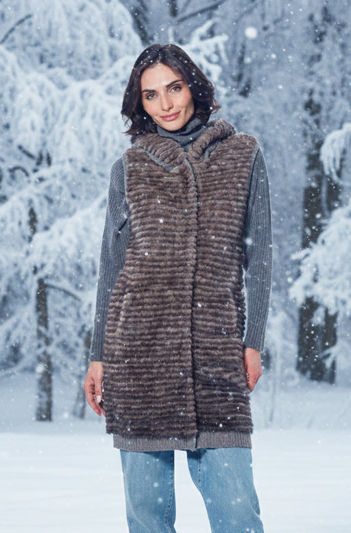 Woman wearing a long fur vest in a snowy forest
